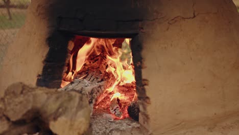 un tatakua, un horno de arcilla tradicional hecho a mano de paraguay, con llamas de madera calentando el horno para luego hornear alimentos típicos