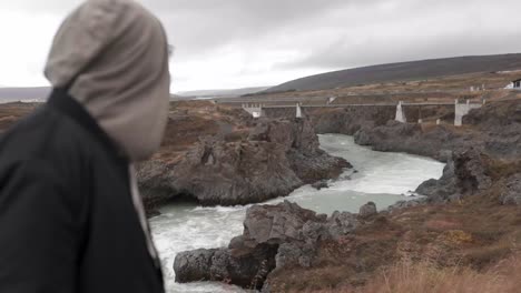 Traveler-admiring-view-of-bridge-over-river-in-highlands