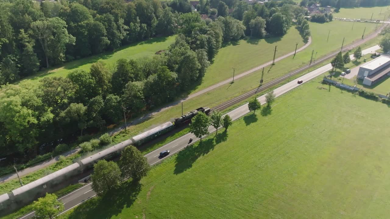 자동차와 오토바이가 증기 열차와 평행하게 달린다