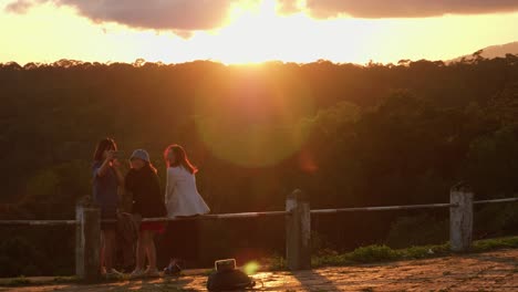 jóvenes asiáticas sentadas en la baranda sobre el valle viendo la puesta de sol con bengalas, vietnam