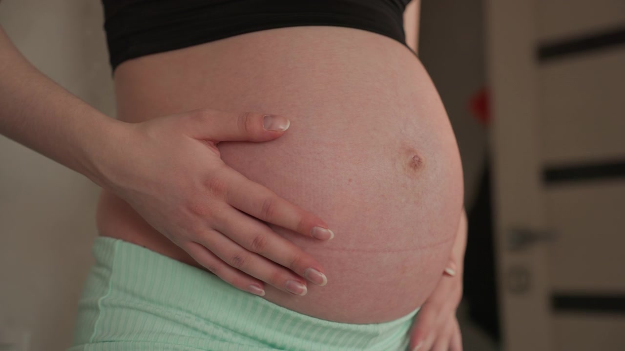 Donna incinta che si tocca delicatamente la pancia