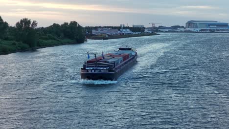 progresso dordrecht cargo vessel with multiple containers leaving harbor site of dordrecht city, zuid-holland, netherlands