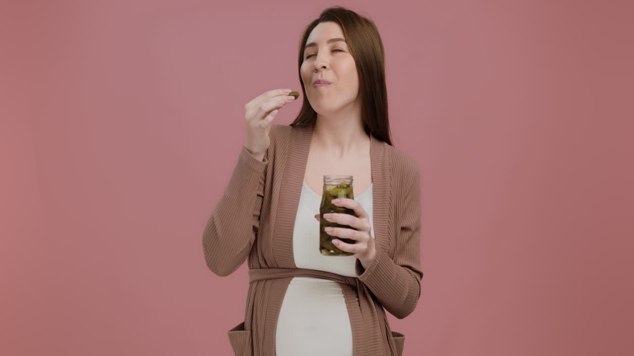 임신 한 여자 가 피클 을 먹고 있다