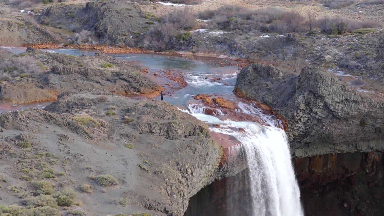 Approaching aerial fly to the Salto del Agrio waterfall top side where flowing the river between rocky environment, Neuquén, Argentina