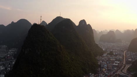 4k-drone-sunset-above-chinese-city-with-mountains-guilin-yangshuo-zoom-out