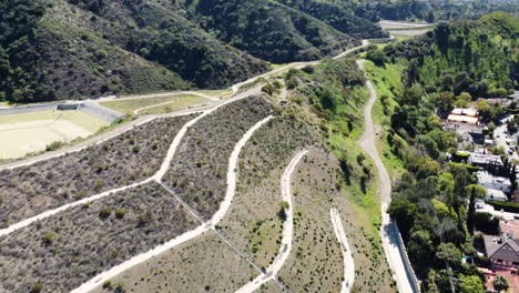 aerial drone forward moving shot of winding road and posh mansions along the hillside in beverly hills, california, usaon a bright sunny day