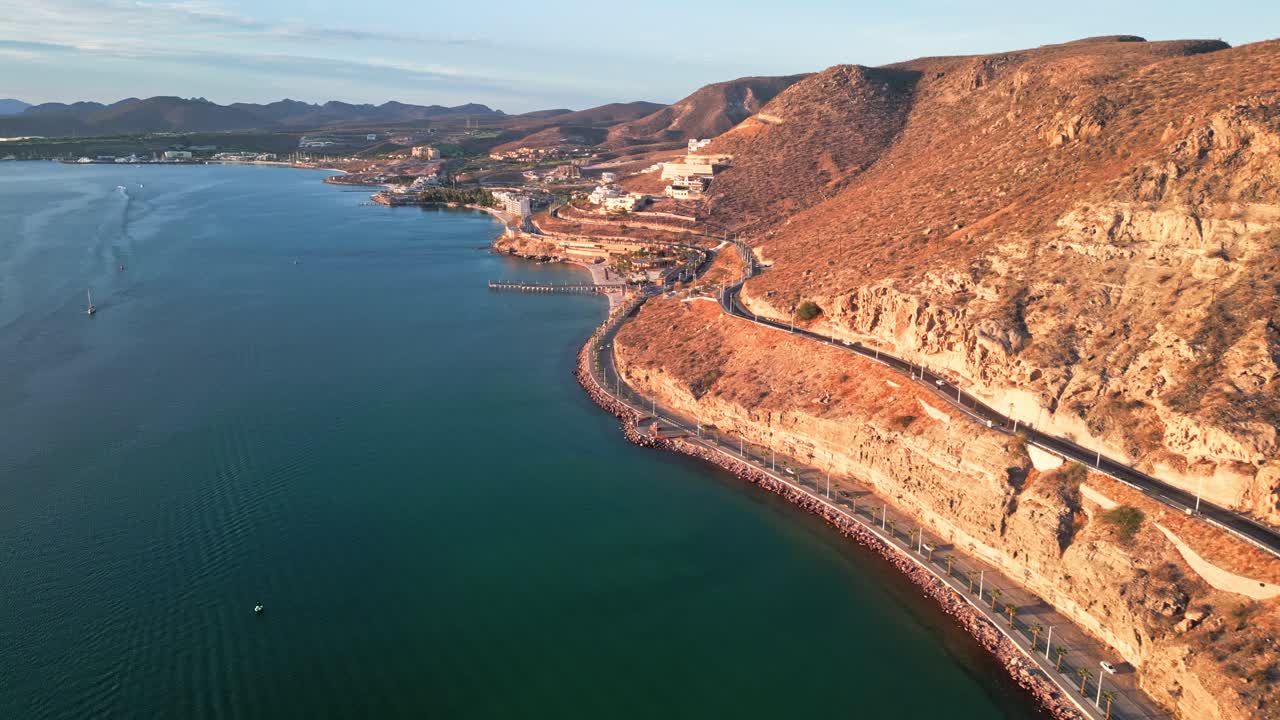 Winding coastal road by rocky hills, La Paz Malecon Calavera at sunset, Baja Mexico