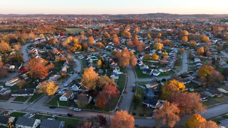 american neighborhood with quaint houses among colorful fall foliage during autumn sunset