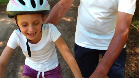 abuelo enseñando a su nieta a montar una bicicleta