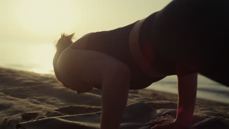 athletic girl training flexibility making yoga exercises on seashore close up.