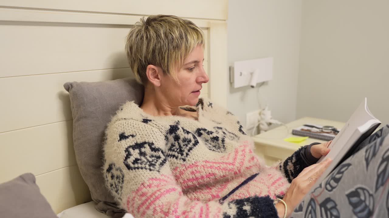 Kvinne som leser en bok i sengen