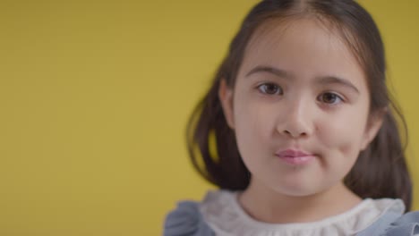 retrato de estudio de una joven tímida sonriendo y riendo contra un fondo amarillo 1