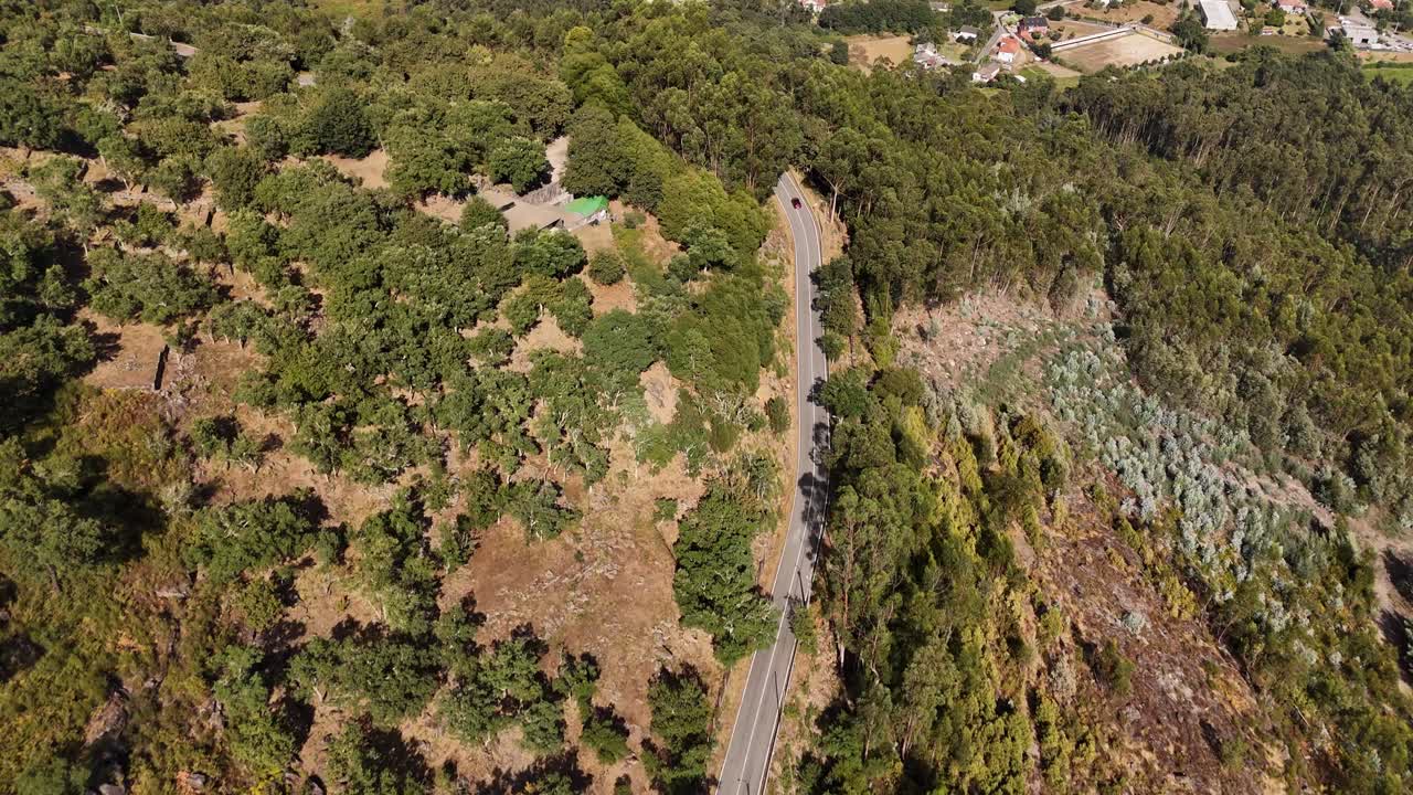 winding road through a hilly, forested terrain in Minho, North Portugal - aerial