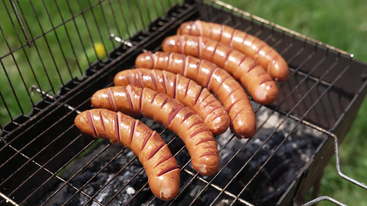 Juicy sausages frying on a fire. Sausages grilling on the barbecue. Hot delicious meat.