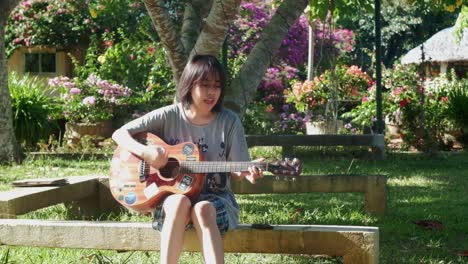person playing acoustic guitar in a sunny garden