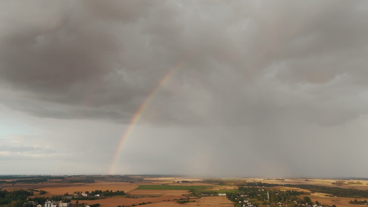 The Rainbow Over the Green Field After Storm With Rain, During Outumn, Aerial View Under Heavy Clouds Before Thunderstorm. Agriculture Landscape Many Crop Fields. Aerial 4k Shot