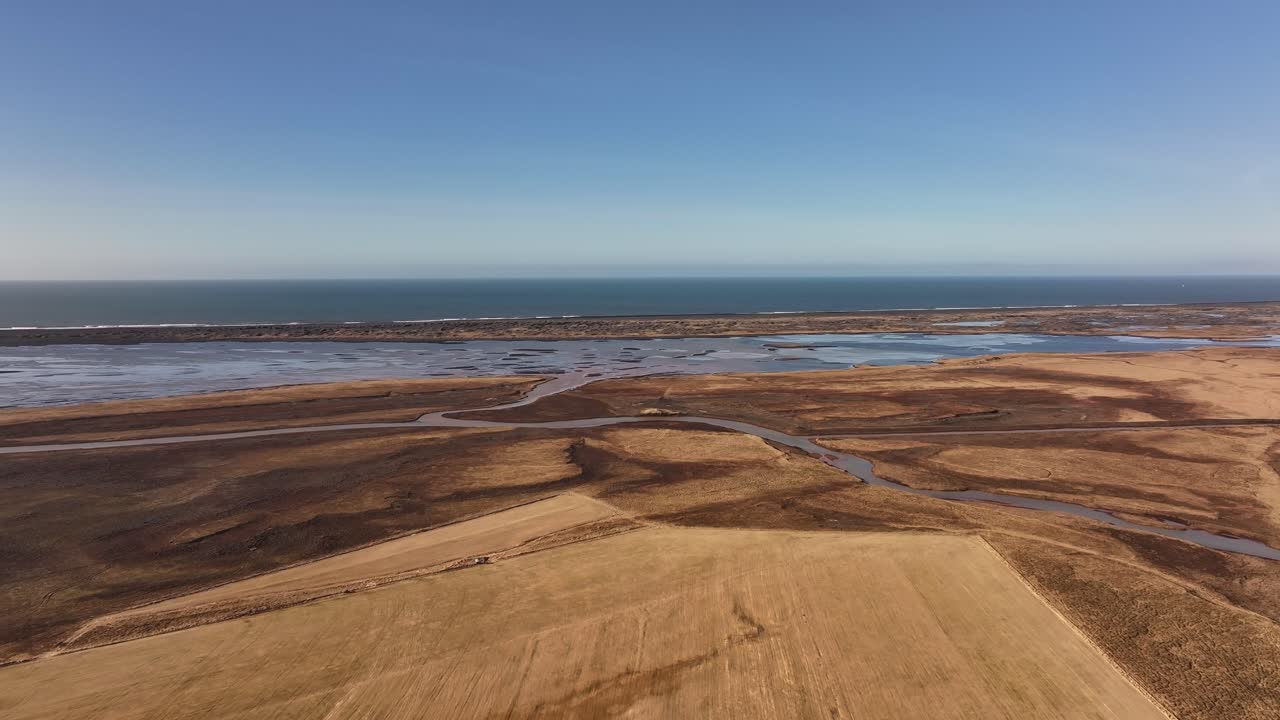 Aerial view of Þjórsá River, Iceland, winding through vast golden fields and wetlands towards the North Atlantic Ocean.