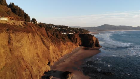 drone flies around cliff at the beach at golden hour