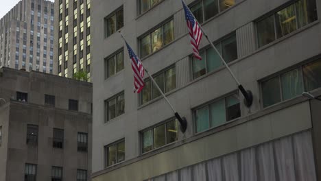 edificio de la ciudad de nueva york con dos banderas estadounidenses ondeando en el distrito financiero de manhattan