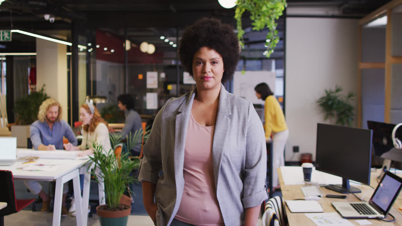 ritratto di una donna d'affari bi-razziale felice che guarda la telecamera in ufficio