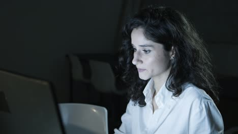 Serious-businesswoman-using-computer-in-dark-office