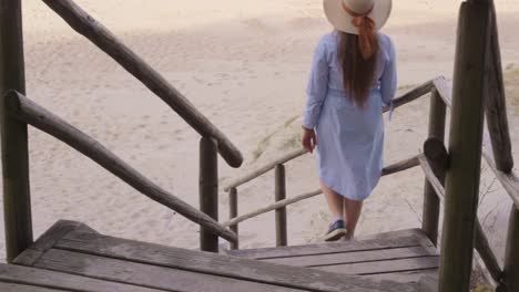 chica despreocupada camina por la escalera de madera en la playa, vacaciones en verano