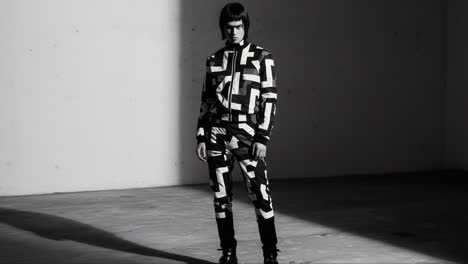 a fashion model poses in a bold patterned outfit, captured in dramatic lighting in a minimalist studio environment, creating a striking visual impact
