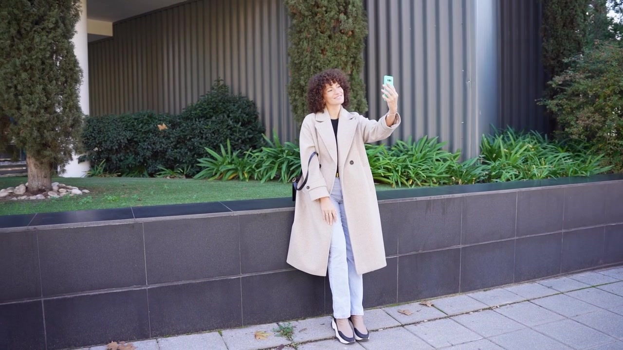 Una donna elegante in piedi all'aperto mentre tiene un caffè, vestita con un cappotto alla moda