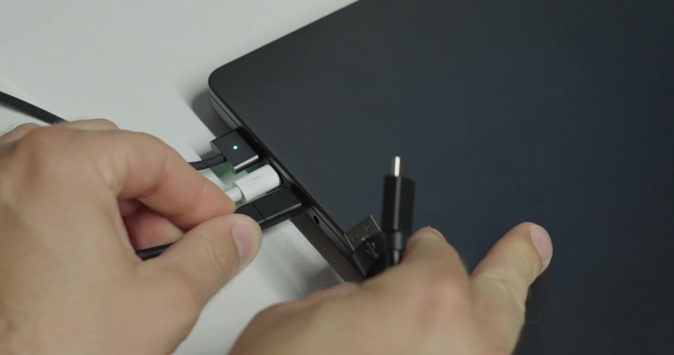 Persona che cerca di collegare un altro dispositivo USB a un laptop con tutte le porte già occupate, illustrando connettività limitata e porte USB insufficienti