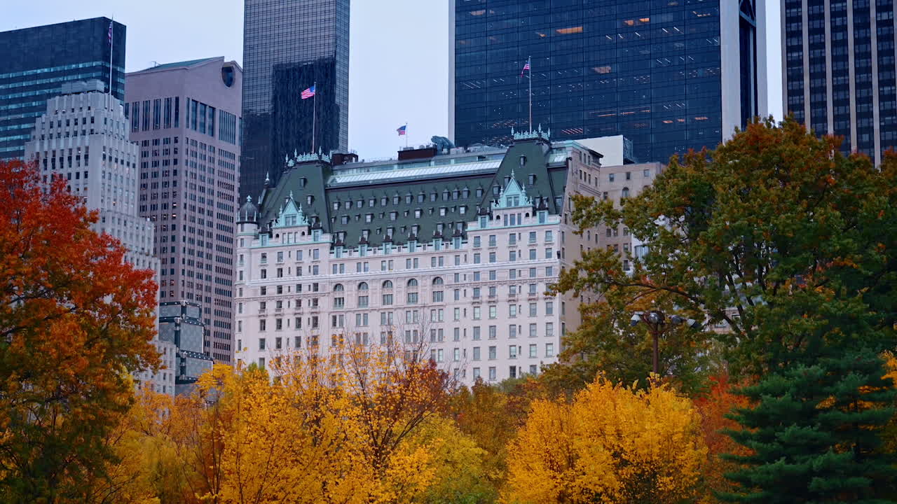 Beautiful building of the Plaza Hotel in New York in the skyline of the city. Bright autumn trees of Central Park at foreground