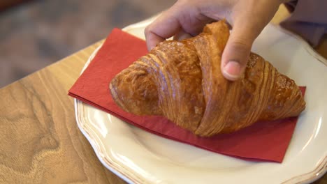 close up of a croissant on a white plate with a red napkin