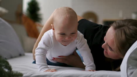 happy family. mother playing with her baby in the bedroom.