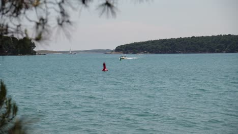 speedboats and jet-ski travelling at speed near coastline in small peninsula