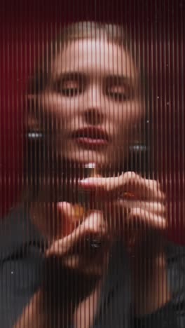 woman in black clothing behind a red glass wall