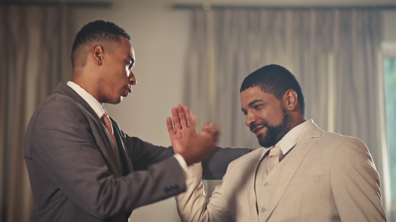 Two Men in Suits Interacting and Embracing at a Formal Event