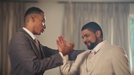 Two Men in Suits Interacting and Embracing at a Formal Event