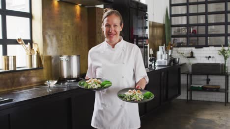 Caucasian-female-chef-preparing-a-dish-and-smiling-in-a-kitchen-