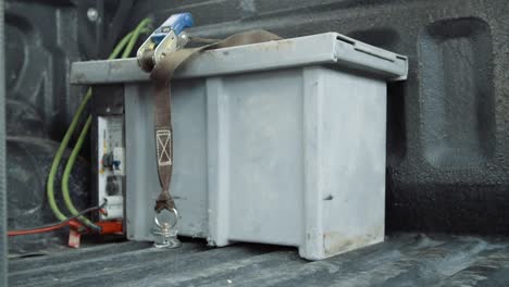 static shot of a strapped down fridge battery in the back of off-road vehicle.