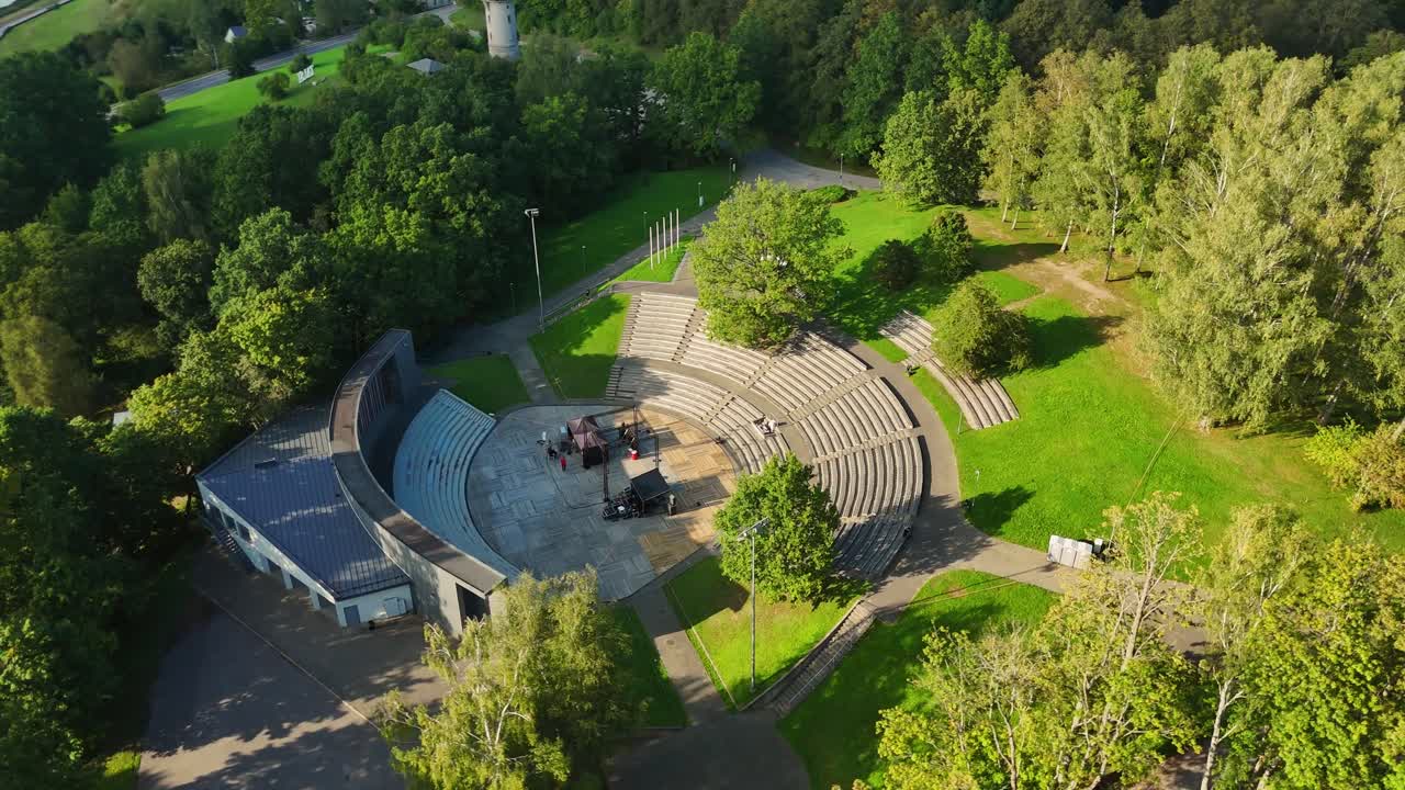Aerial drone perspective revealing Sauleskalns Sun hill amphitheater, nestled amid verdant parkland, highlighting architectural design within Riga, Latvia's green urban landscape