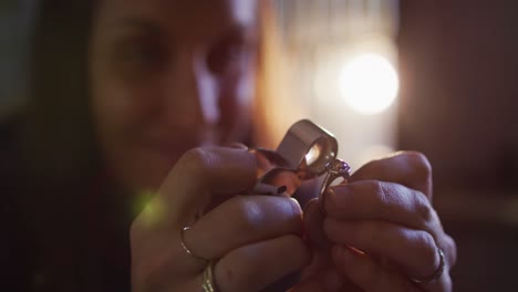 Close-up-of-caucasian-female-jeweller-checking-quality-of-jewelry-in-workshop