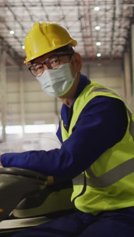 portrait of asian male worker wearing safety suit and face mask in warehouse