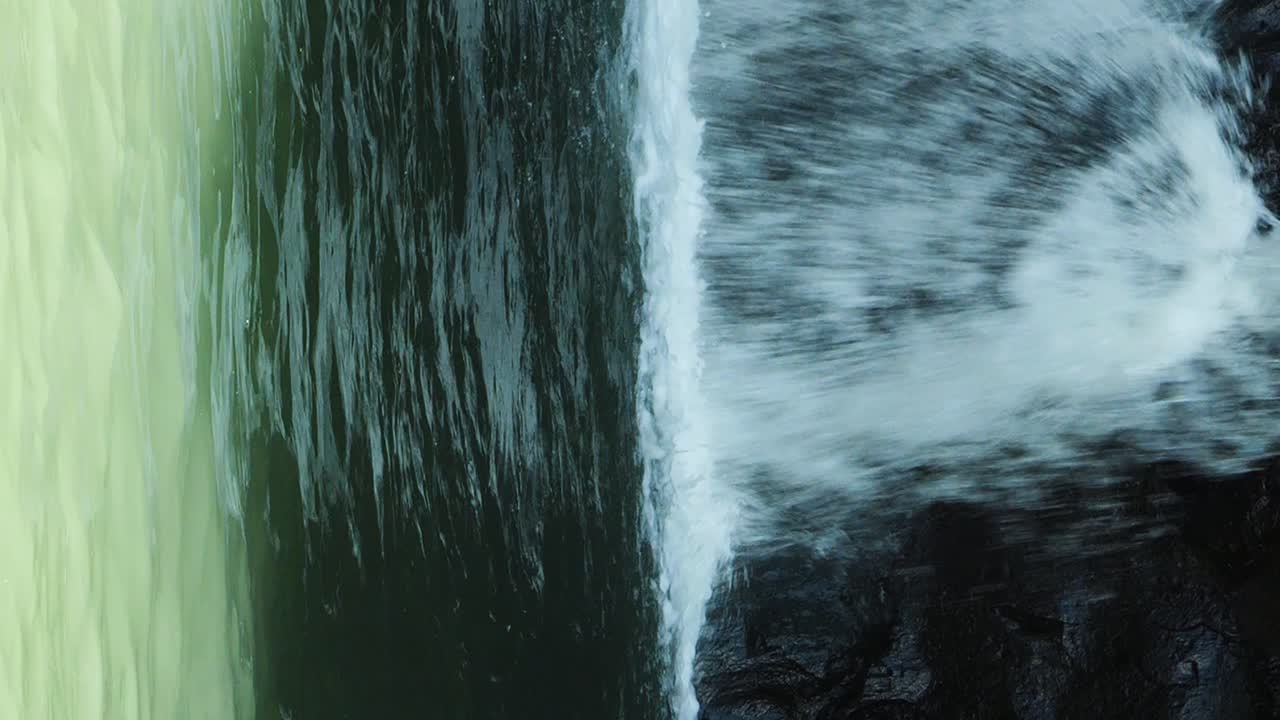toma de mano de una cascada en bali en ubud, indonesia, con vistas a las rocas oscuras en el medio de la selva