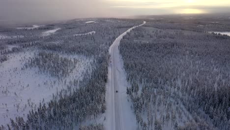 Coche-Aéreo-Delantero-Conduciendo-En-Una-Carretera-Invernal-Cubierta-De-Nieve,-Campo-Rural,-Suecia,-Tiro-Panorámico