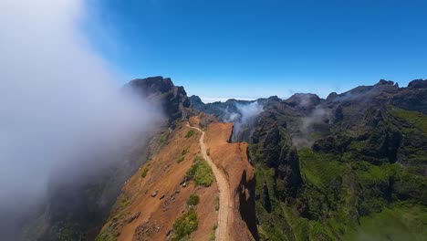 drone following pico do pico hiking trail along mountain ridge with steep cliffs on both sides