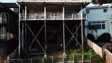 White-house-close-up-on-stilts-stands-3-stories-high-off-the-ground-on-a-steep-mountain-incline