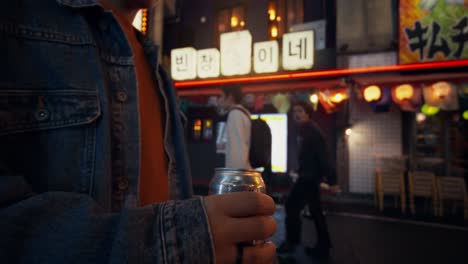 person enjoying a drink on a japanese street at night