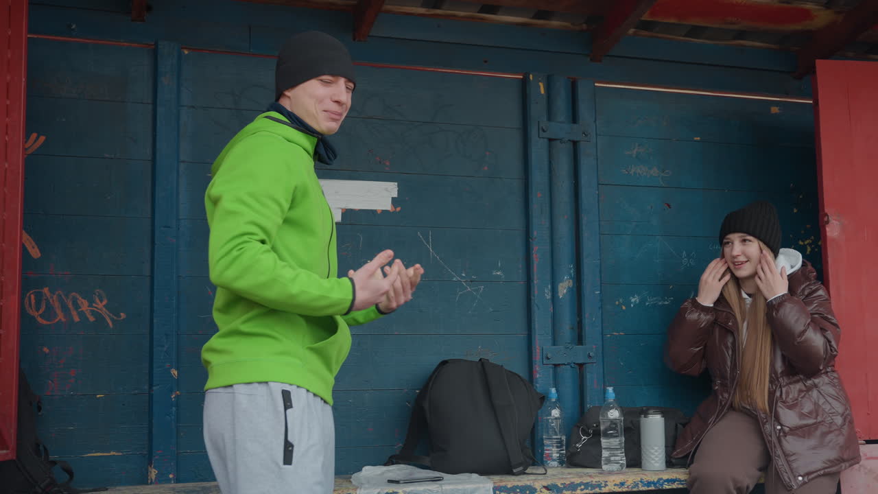 활기찬 남성이 장난기 넘치는 춤을 추고, 후드티를 입은 남성이 도시를 배경으로 활발한 춤을 선보이며 즐거움을 선사하고, 초록색 후드티를 입은 남성 공연자가 도시 쉼터 계단에서 여성 앞에서 생동감 넘치는 춤을 춰요