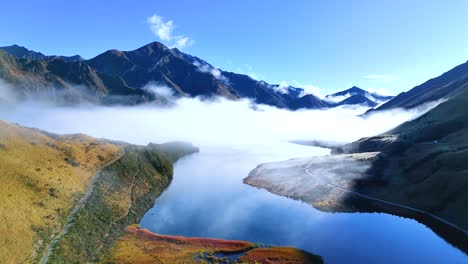 Aerial footage of Moke Lake in Queenstown, New Zealand, showcasing serene mountains and fog. Bright daylight enhances the tranquil atmosphere