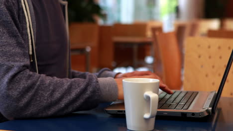 student typing on his laptop