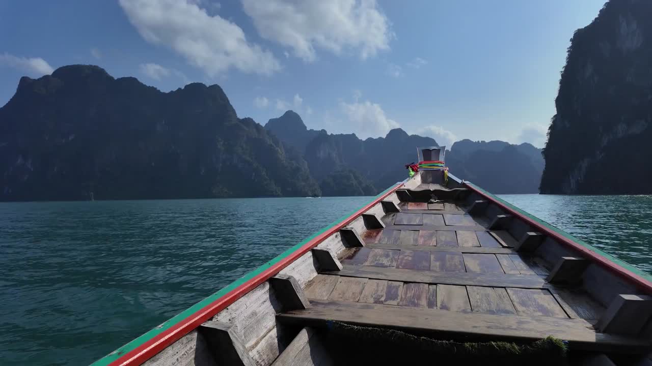 태국 카오소크 국립공원 (khao sok national park) 의 그림 같은 열대 산들 사이에서 물 위를 항해하는 전통적인 목조 보트.
